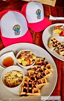 a table with plates of food and bowls of food at The Beach Break Hotel El Zonte in El Zonte