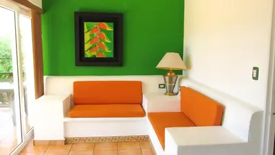 a living room with green walls and an orange chair at Las Veraneras Villas & Resort in Acajutla
