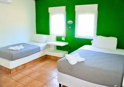 a room with two beds and a green wall at Las Veraneras Villas & Resort in Acajutla