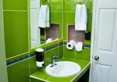 a green bathroom with a sink and a mirror at Las Veraneras Villas & Resort in Acajutla