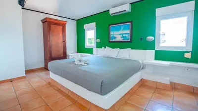 a green bedroom with a bed with a teddy bear on it at Las Veraneras Villas & Resort in Acajutla