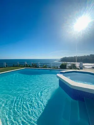 a swimming pool with the ocean in the background at Paradise Surf Hotel in San Miguel