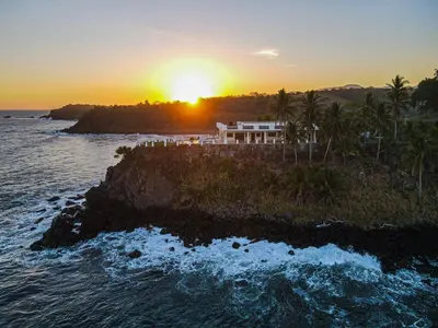 a house on a cliff near the ocean at sunset at Paradise Surf Hotel in San Miguel
