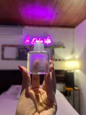 a person holding a perfume bottle in a bedroom at VILLA NAPOLI in Santa Ana