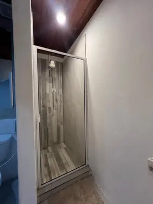 a glass shower in the corner of a bathroom at VILLA NAPOLI in Santa Ana