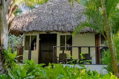 a house with a thatched roof with a dog sitting in the doorway at Hotel Martinez in Conchagüita