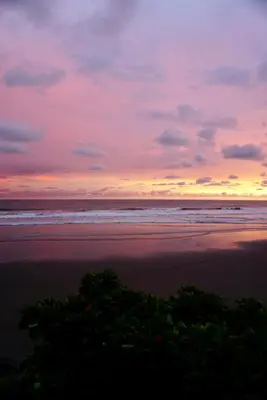 a sunset on a beach with the ocean at Vista Las Olas Resort in El Cuco