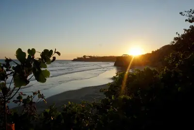 a sunset on a beach with the sun setting at Vista Las Olas Resort in El Cuco