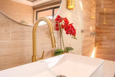 a bathroom sink with a faucet and red flowers at Vista Las Olas Resort in El Cuco