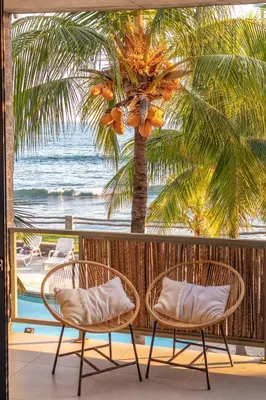 two chairs and a palm tree on a balcony with the ocean at Fishermans Resort Life in La Libertad