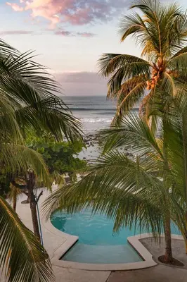 a swimming pool with palm trees on the beach at Fishermans Resort Life in La Libertad