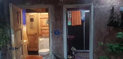 a small bathroom with a toilet and a door at Mendoza’s GUESTHOUSE in Santa Ana