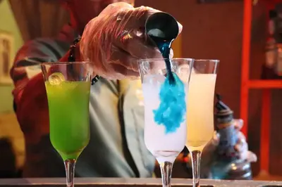 three drinks on a table with a person pouring liquid at Hotel Brunette in Santa Ana