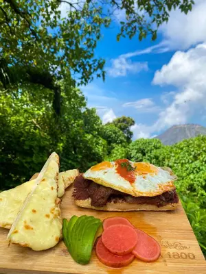 a wooden cutting board with a sandwich with an egg and bread at Casa 1800 Cerro Verde in Cerro Verde