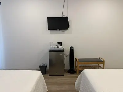 a room with two beds and a television on the wall at Lali Beach Hotel Boutique in Sonsonate