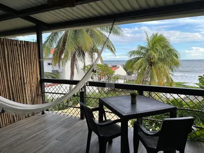 a hammock on a porch with a table and chairs at Lali Beach Hotel Boutique in Sonsonate