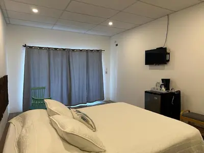 a bedroom with a bed with a tv and a window at Lali Beach Hotel Boutique in Sonsonate