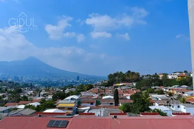 a city with buildings and a mountain in the background at Volcano Views Apartment in San Salvador