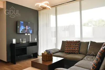 a living room with a couch and a flat screen tv at Infinity Pool Apartment in San Salvador