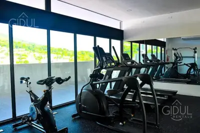 a gym with cardio equipment in a building with windows at Infinity Pool Apartment in San Salvador
