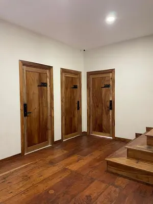 an empty room with three doors and wooden floors at Hotel Finca San Nicolas in San Salvador