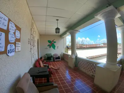 a man sitting on the balcony of a restaurant at Ricks hostel Santa Ana in Santa Ana