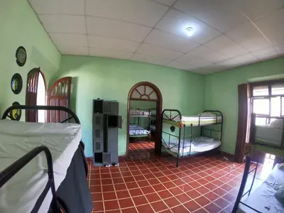 a room with three bunk beds in a room with green walls at Ricks hostel Santa Ana in Santa Ana