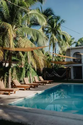 a pool with chairs and palm trees next to a building at Casaola Mizata in Santa María Mizata