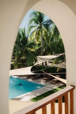 a window with a view of a pool and palm trees at Casaola Mizata in Santa María Mizata