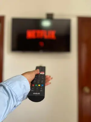 a person holding a remote control in front of a tv at Kali Hotel in Santa Ana