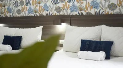 a bedroom with a white bed with pillows and a wallpaper at Kali Hotel in Santa Ana