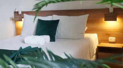 a bedroom with a bed with white sheets and green pillows at Kali Hotel in Santa Ana