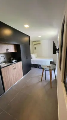 a room with a bed and a table and a kitchen at The Cabins in La Libertad