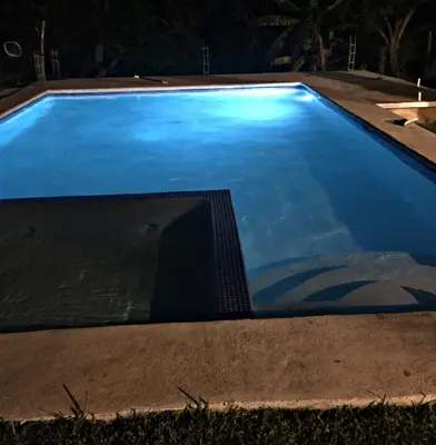 a swimming pool at night with blue water at La Leona 1 in El Zonte