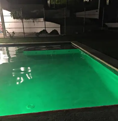 a swimming pool with green water at night at La Leona 1 in El Zonte
