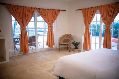 a bedroom with orange curtains and a bed and a table at Casa del Golfo El Salvador in Conchagua