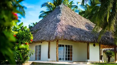 a cottage with a thatched roof and palm trees at Casa del Golfo El Salvador in Conchagua