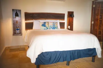 a bedroom with a white bed with a wooden headboard at Casa del Golfo El Salvador in Conchagua