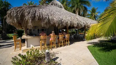 a group of people sitting at a bar in a straw hut at Casa del Golfo El Salvador in Conchagua