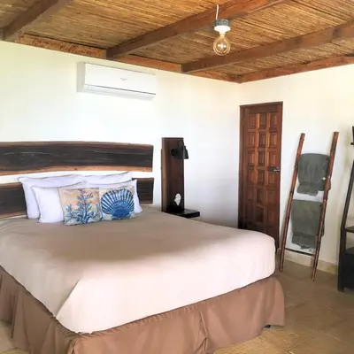 a bedroom with a large bed and a wooden ceiling at Casa del Golfo El Salvador in Conchagua