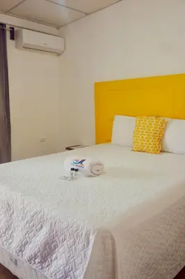 a bedroom with a large white bed with a yellow headboard at Hotel Tunco Lodge in La Libertad