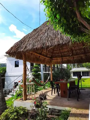 a patio with a hut with a table and chairs at Hotel Tunco Lodge in La Libertad
