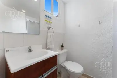 a white bathroom with a sink and a toilet at The Cozy Apartment in San Salvador