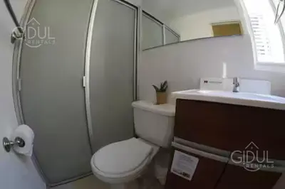 a bathroom with a toilet and a sink and a mirror at The Cozy Apartment in San Salvador