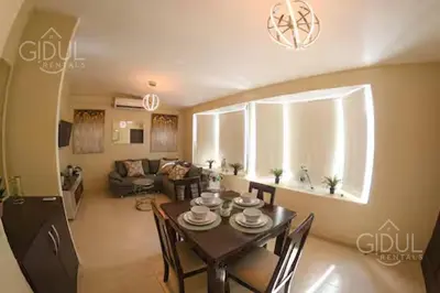 a dining room and living room with a table and chairs at The Cozy Apartment in San Salvador