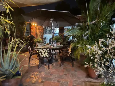 a table and chairs with an umbrella in a garden at Mendoza’s GUEST HOUSE in Santa Ana