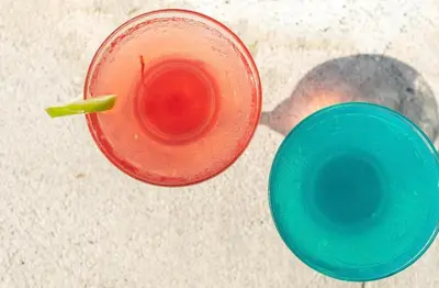 a red drink with a green straw sitting next to a cup at amaremar in San Luis