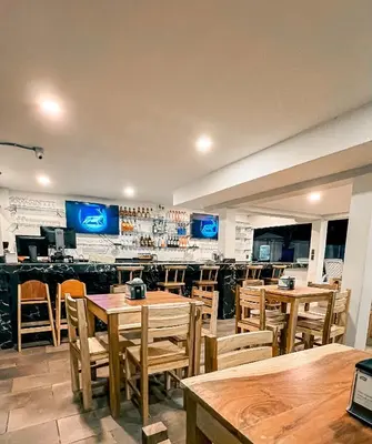 a restaurant with wooden tables and chairs and a bar at amaremar in San Luis