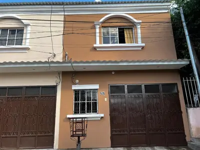 a house with two brown doors and two windows at A 5 minutos de las Ruinas del Tazumal, Chalchuapa Santa Ana El Salvador in Chalchuapa