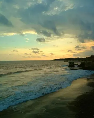 a sunset over the ocean with a pier on the beach at Playa El Obispo F La Libertad Playa El Obispo in La Libertad